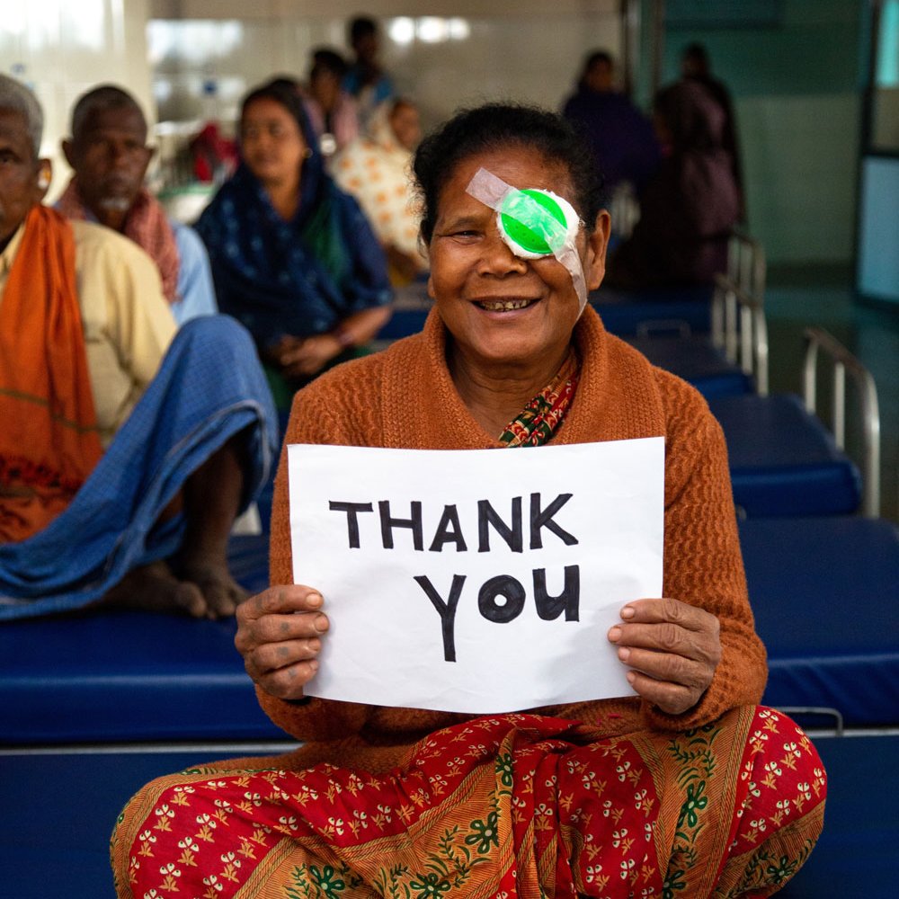 Kishni hält ein Plakat mit den Worten: Thank you in die Kamara. 