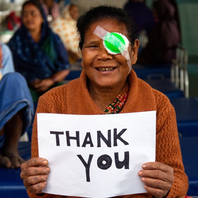 Kishni hält ein Plakat mit den Worten: Thank you in die Kamara. 