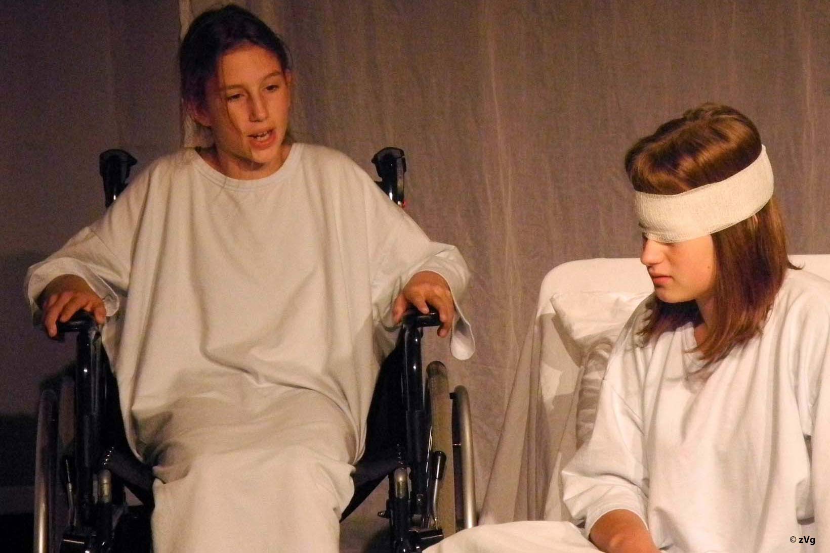 Szene aus Theater für CBM mit zwei Mädchen: eines sitzt im Rollstuhl, das andere ist sehbehindert.
