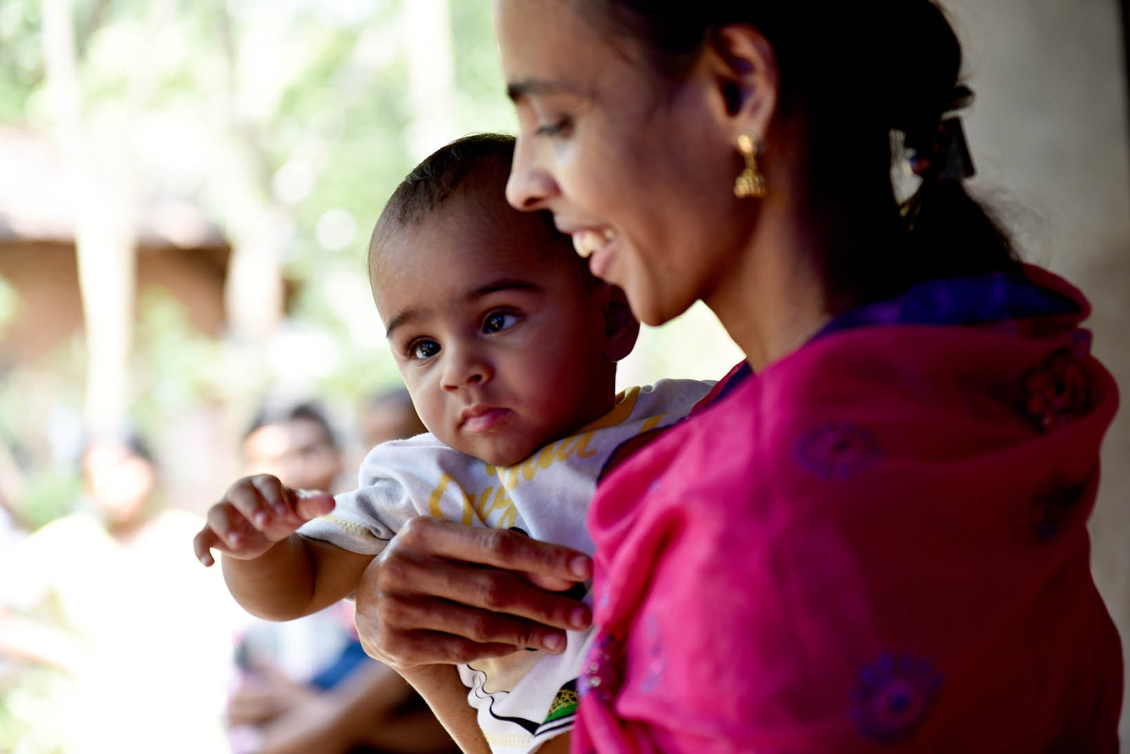 Eine indische Mutter trägt nach der Grauen-Star-Operation ihren kleinen Sohn in den Händen.