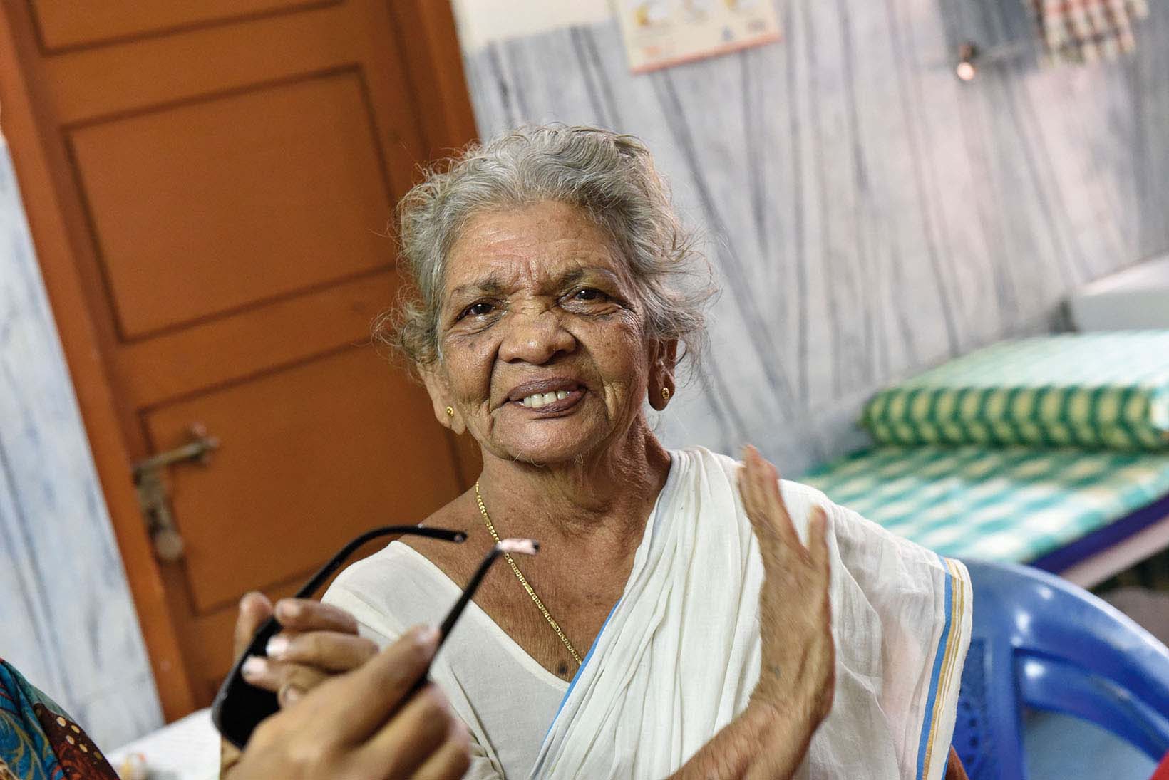 Après son opération de la cataracte, une Indienne d’un âge respectable regarde l’objectif, l’air heureuse. Quelqu’un lui tend des lunettes depuis la gauche.