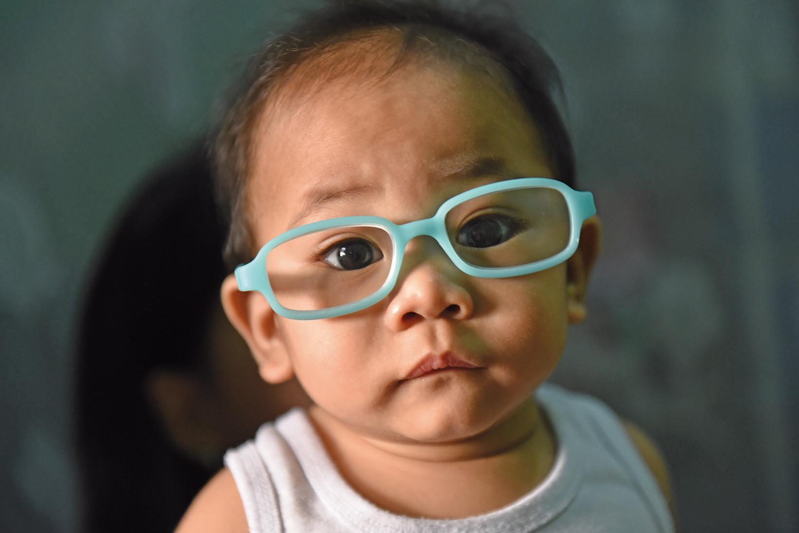 Photo d’un enfant en bas âge avec des lunettes bleu ciel.