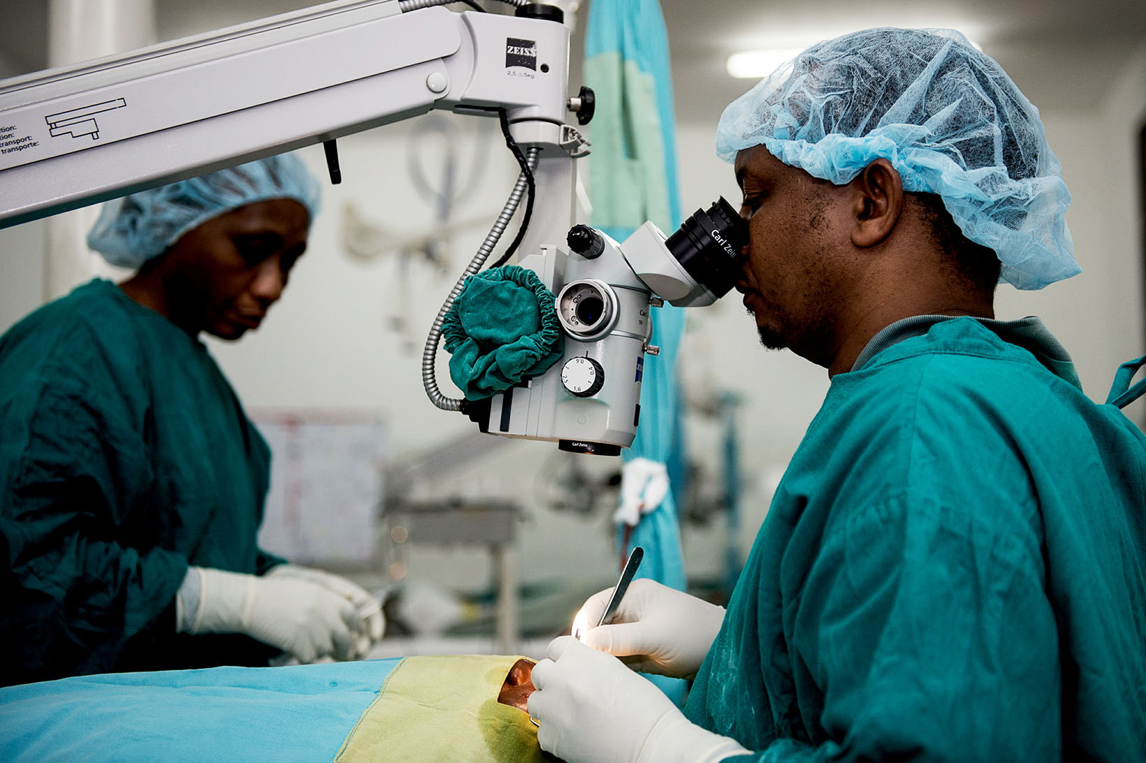 Un chirurgo guarda attraverso un microscopio mentre opera un paziente.