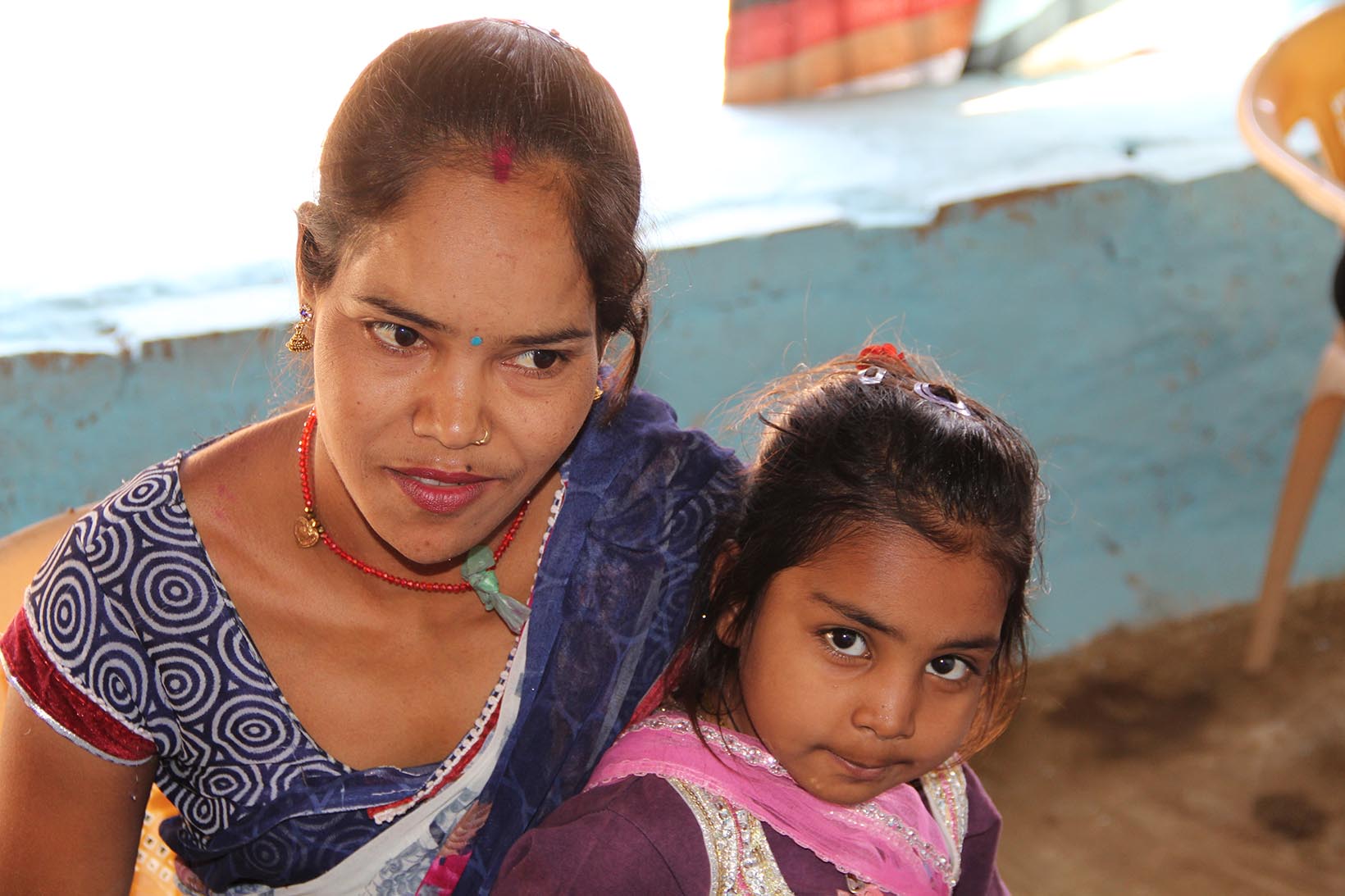 Eine körperlich behinderte Frau aus Indien mit ihrer Tochter.