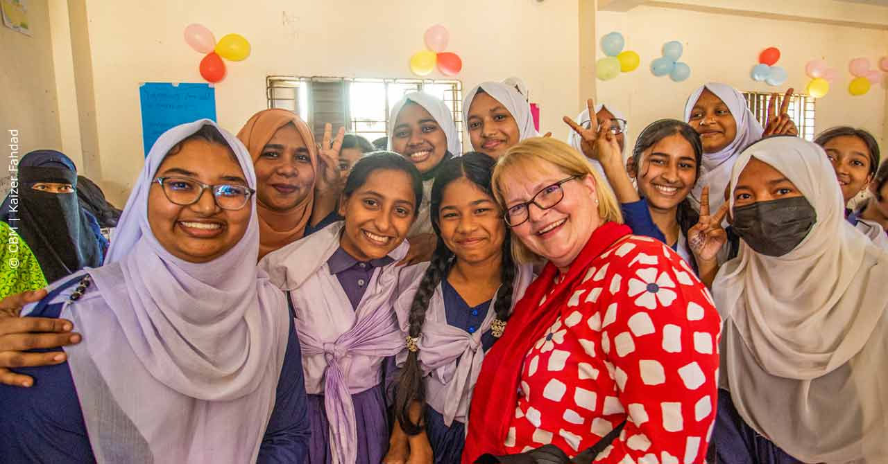 Anja Ebnöther bei einem Projektbesuch in Bangladesch: Das Bild zeigt Mädchen einer Sekundarschule, die zusammen mit Anja Ebnöther in die Kamera schauen. 