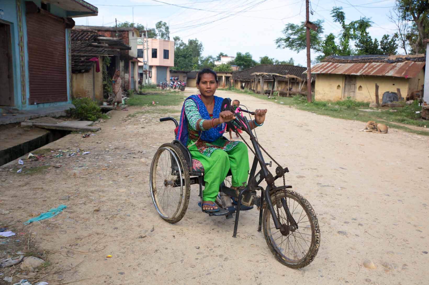 Eine Frau mit Behinderung aus Nepal sitzt auf einem Tricycle. 