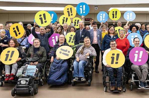 Das Bild zeigt viele Menschen aus den Organisationen, welche die Inklusions-Initiative unterstützen. Sie halten Plakate hoch. 