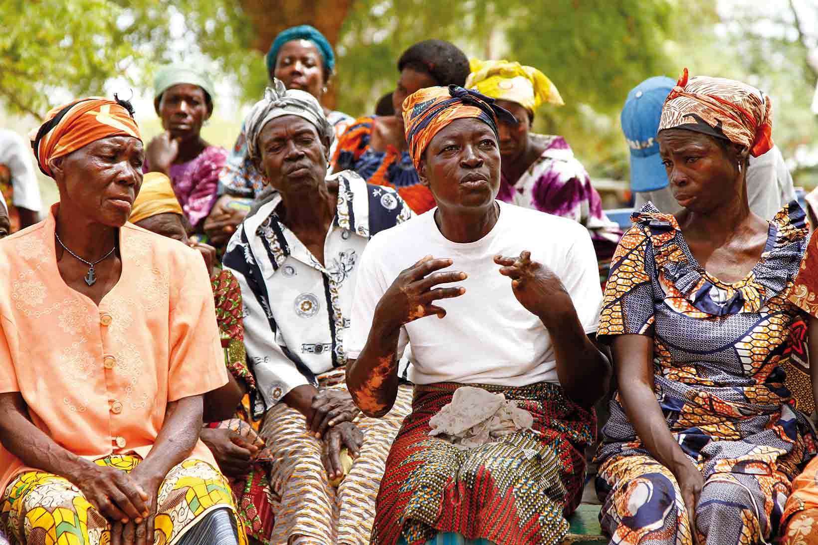 Un gruppo di donne dal Ghana fotografato frontalmente. La donna che parla ha una disabilità fisica.
