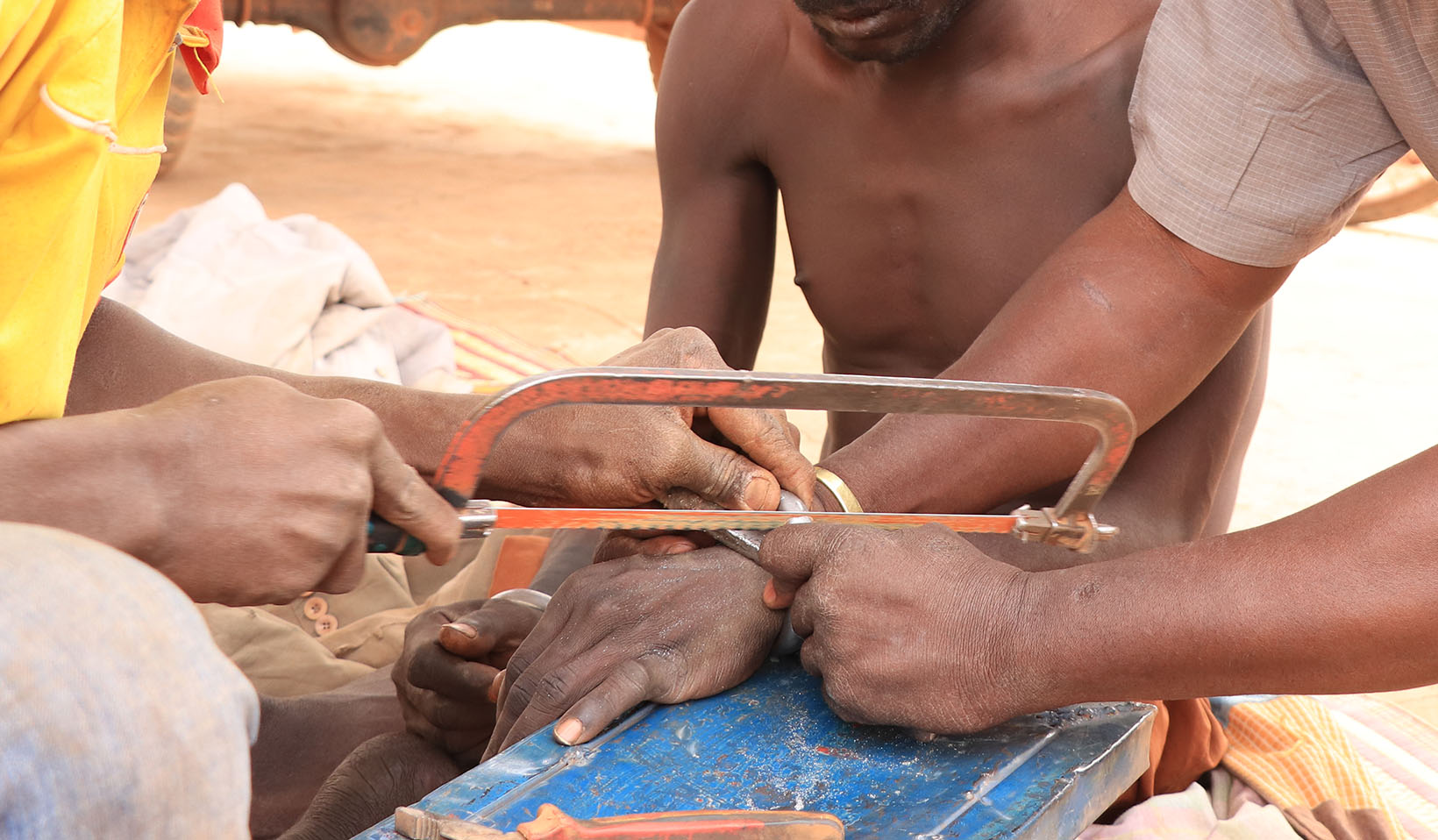 Zwei Männer sagen die Ketten eines psychisch beeinträchtigten Mannes aus Burkina Faso durch.