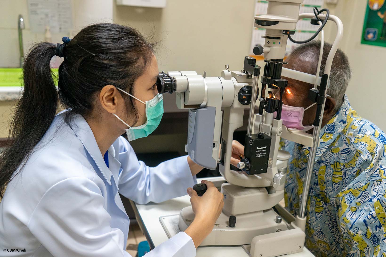 Eine Augenchirurgin aus Laos untersucht mittels Spaltlampe die Augen eines Mannes.