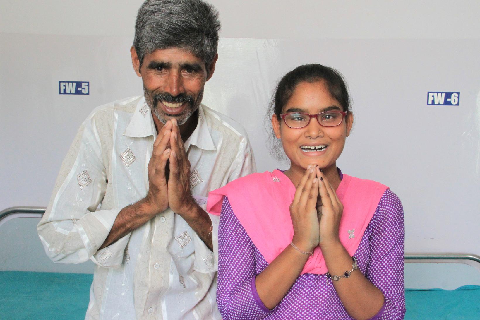 Ein Mann und eine junge Frau haben die Hände zum Dank gefaltet und lächeln breit in die Kamera.