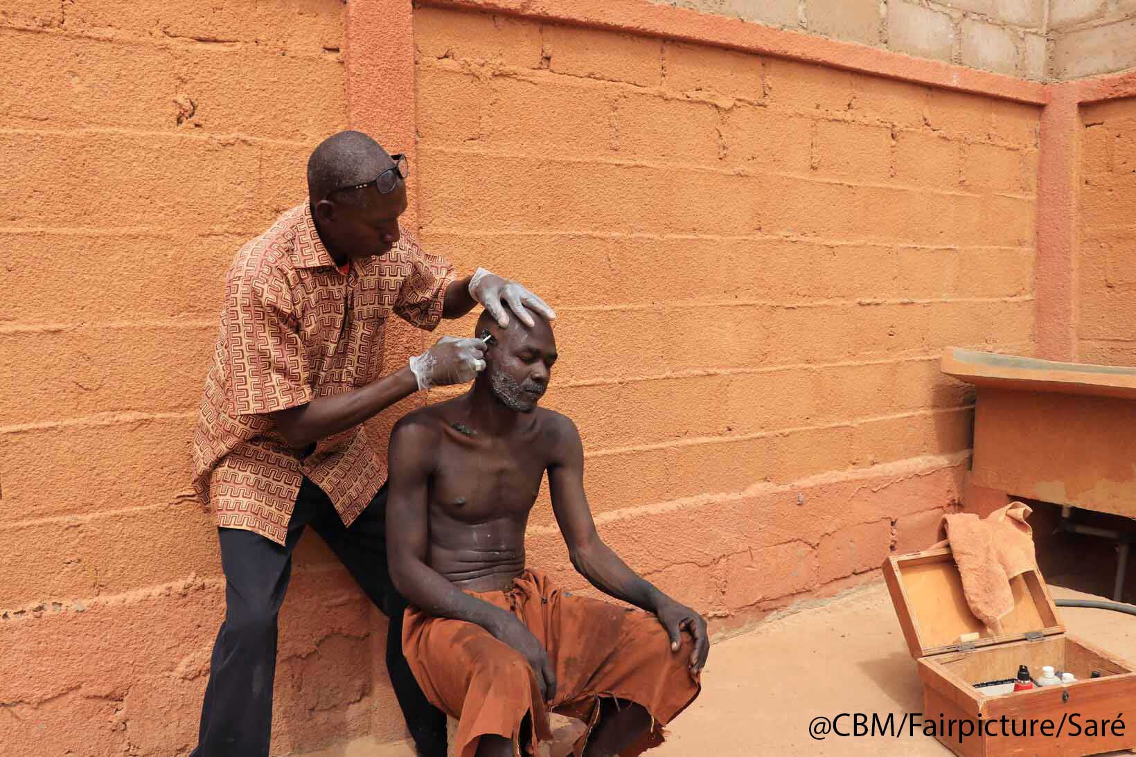 Ein Pfleger des Zentrums SAULER schneidet Ouseni Kindo die Haare. 