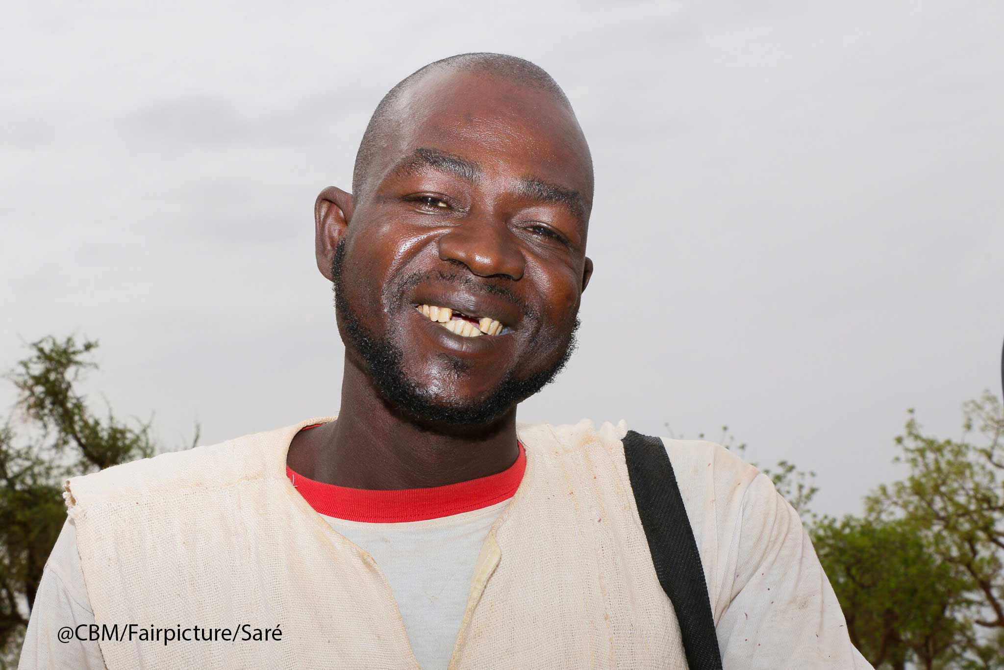 Ein aktuelles Portrait von Ousoeni Kindo. Der 40-jährige Mann schaut glücklich und lachend in die Kamera. 