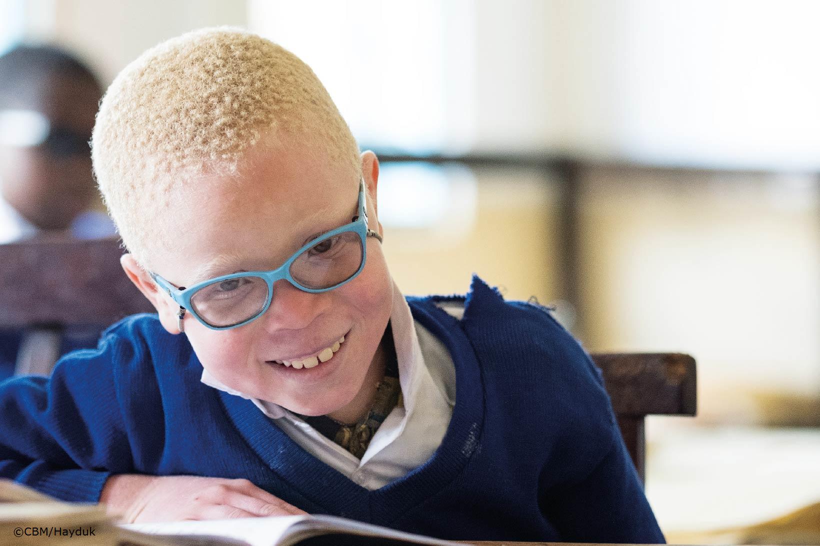 Un jeune garçon du Zimbabwe fixe l’objectif à travers ses lunettes. La lumière du soleil l’éblouit un peu à cause de la récente opération de la cataracte qu’il a subie.