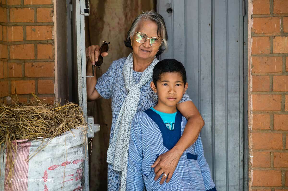 Ranto steht mit seiner Grossmutter am Eingang ihrer Tür. Sie hält schützend den Arm um ihn. 