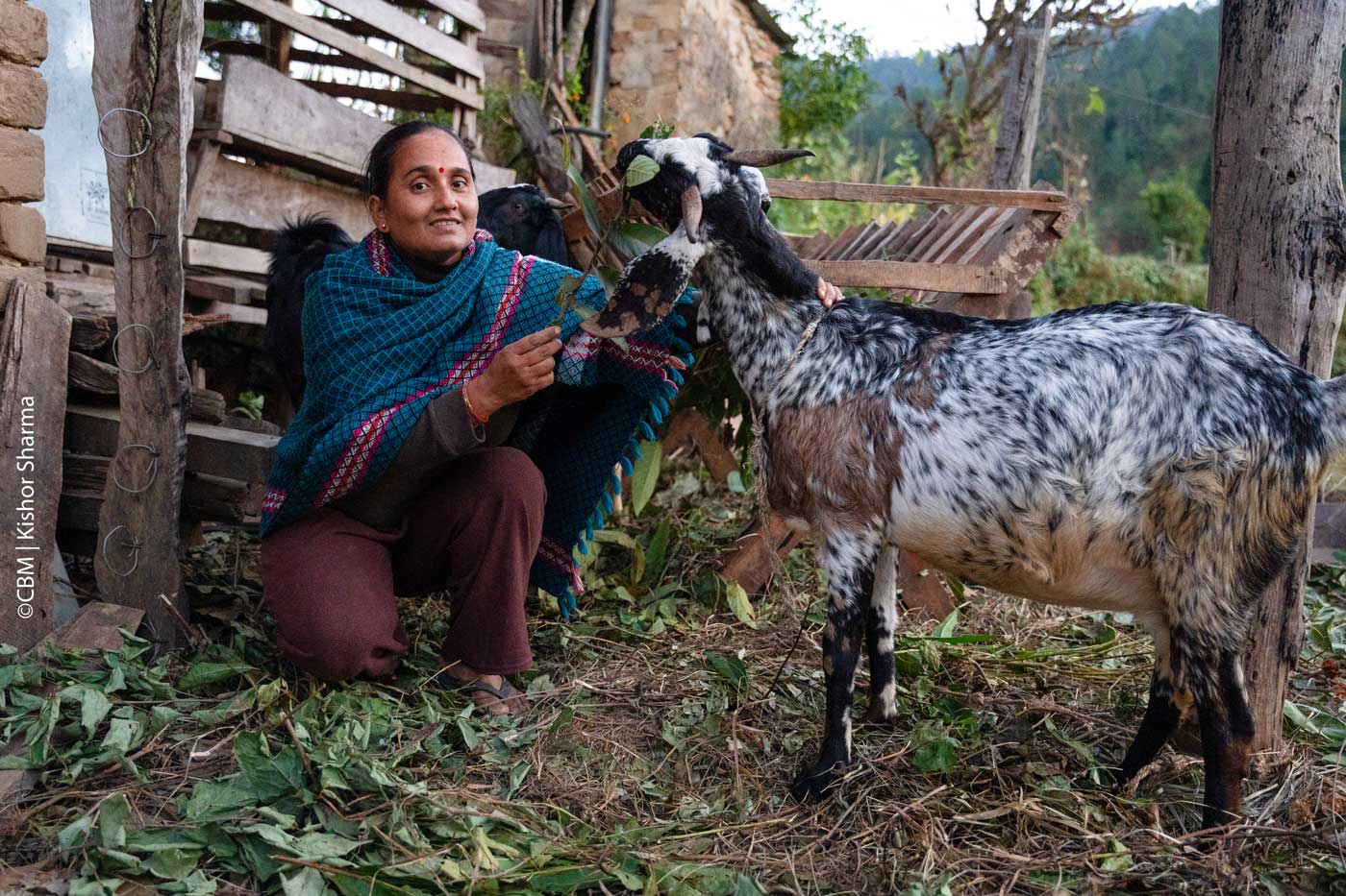 Das Bild zeigt Spana lachend mit einer Ziege. 