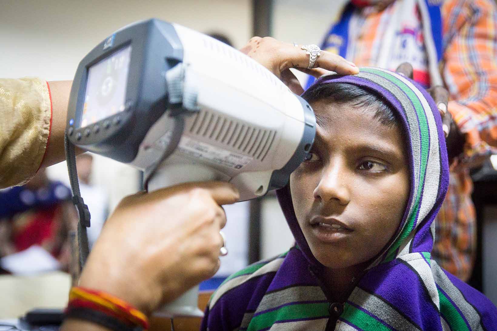 Bei einem Jungen aus Indien wird mit einem Autorefraktometer das Auge untersucht.