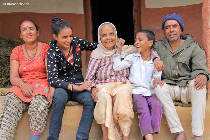 Tika Niraula umrahmt von ihrer Familie. Die Enkelkinder und sie lachen und können kaum fürs Foto still sitzen.