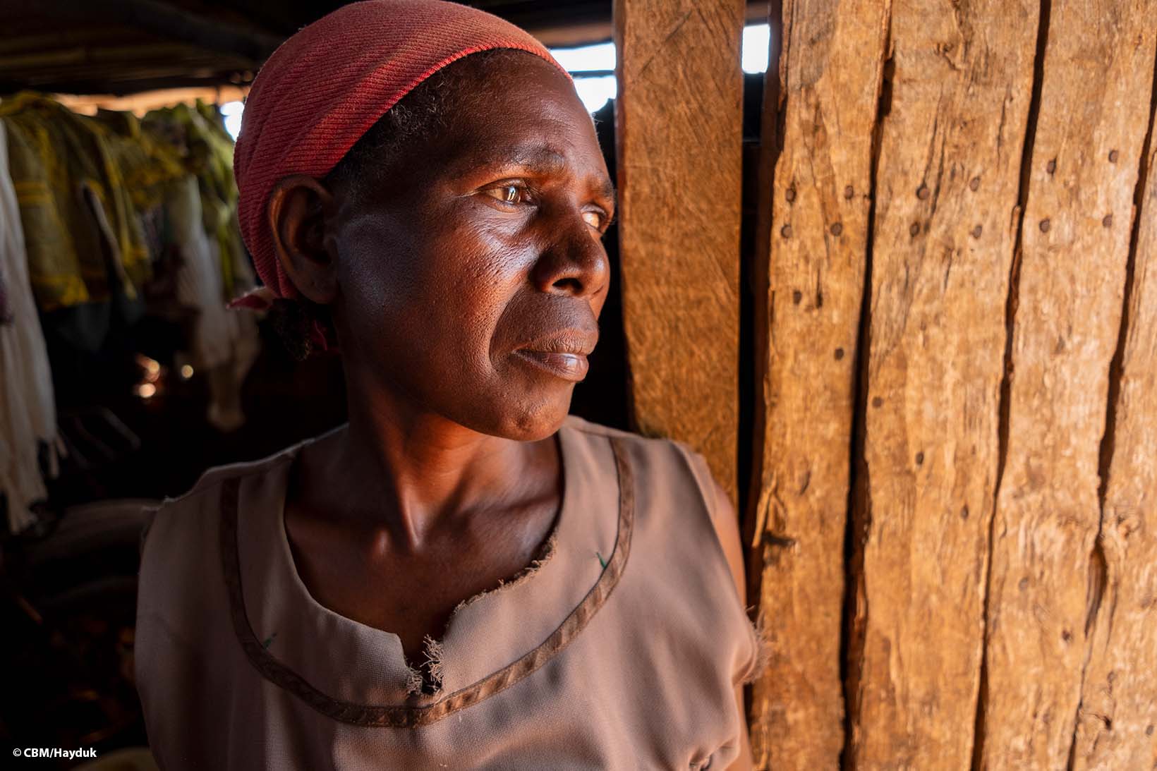 Eine Frau aus Kenia steht im Eingang ihres Häuschens und blickt nach draussen.