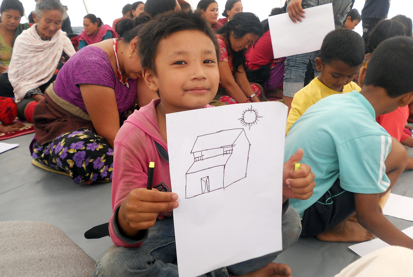 Ein Mädchen aus Nepal zeigt eine Zeichnung eines Hauses. Foto: KOSHISH.