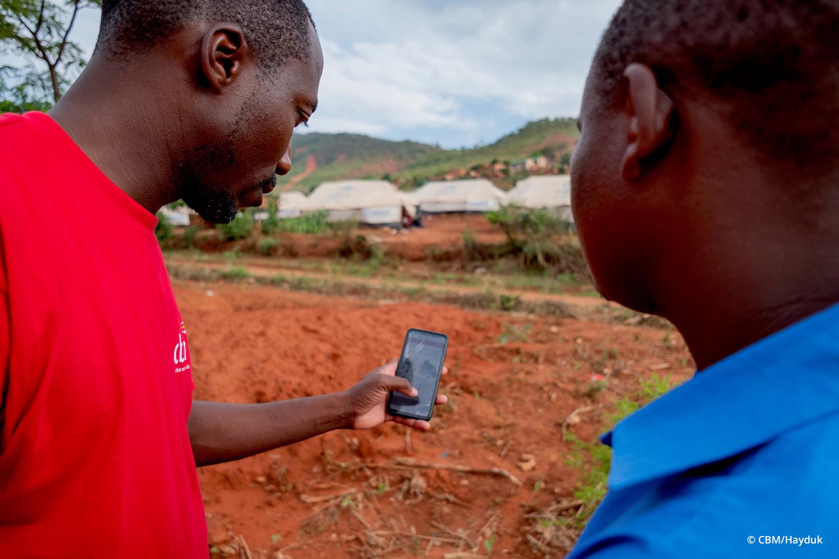 Ein Mann zeigt einem anderen Mann aus Simbabwe etwas auf einem Mobiltelefon.