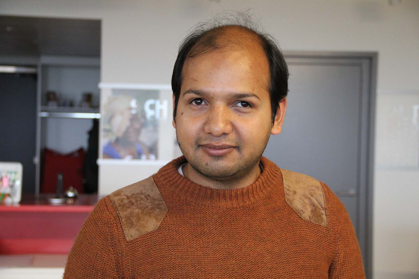 Porträt eines blinden Mannes aus Pakistan, der in einem Büro steht.