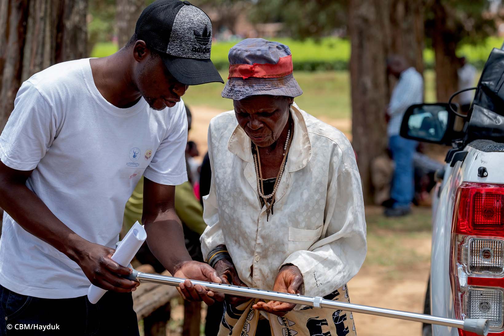 Un Zimbabwéen remet une béquille à une femme âgée. 