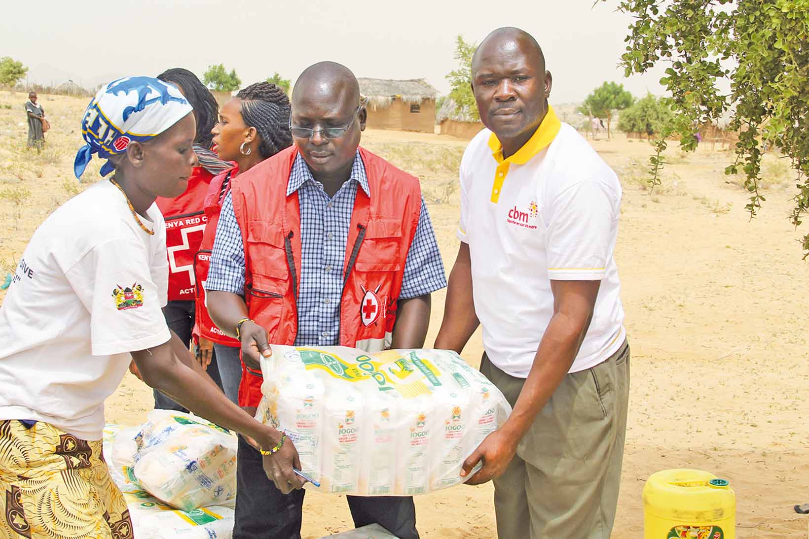 Nothilfemitarbeitende aus Kenia tragen ein Nothilfe-Paket.