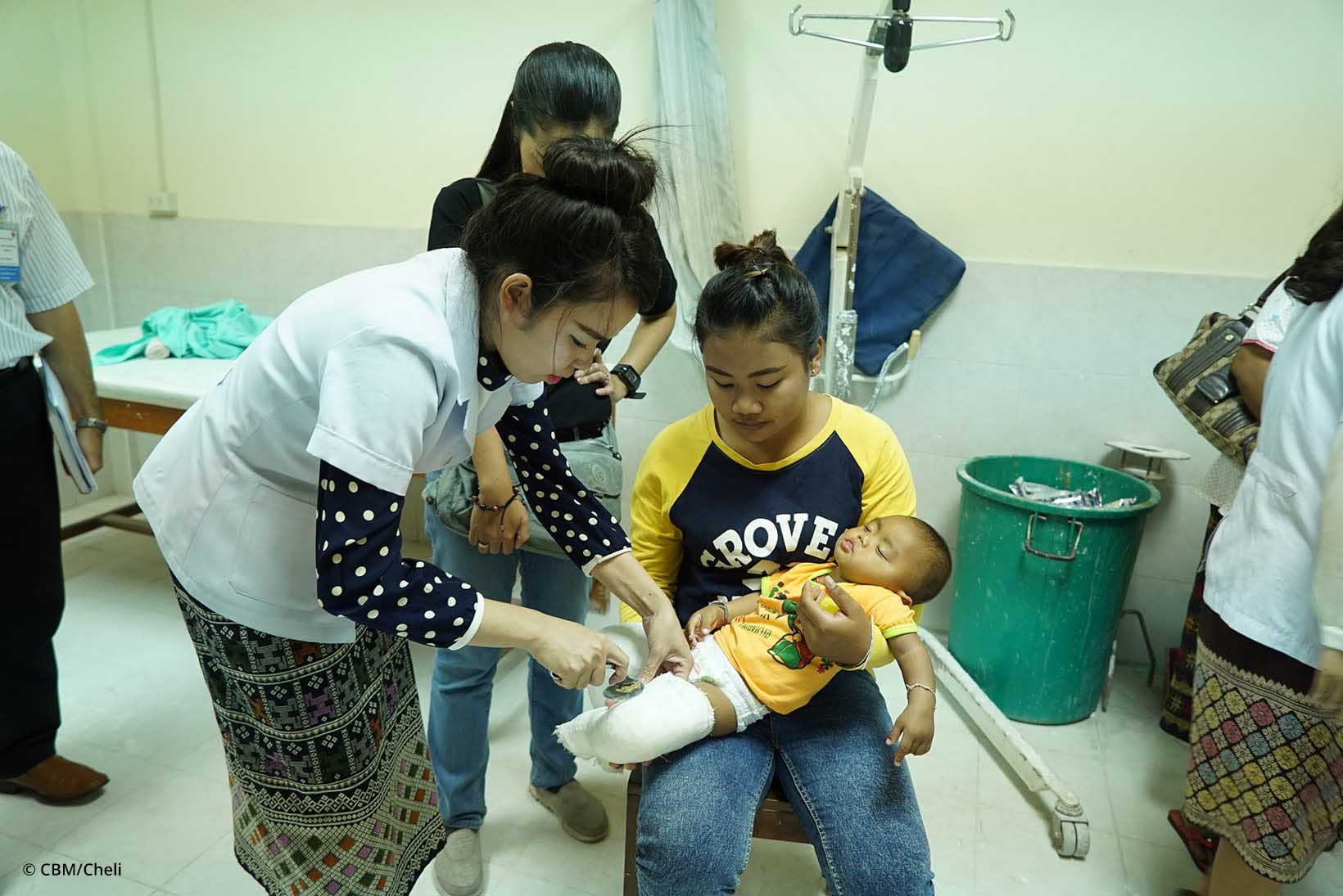 Eine Ärztin wechselt bei einem Baby den Gips.
