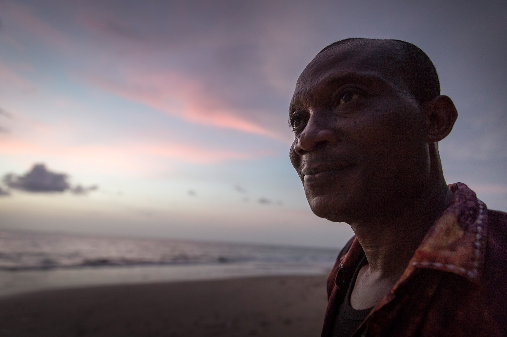 Ein Mann aus Sierra Leone blickt bei Sonnenuntergang ins Meer hinaus. 