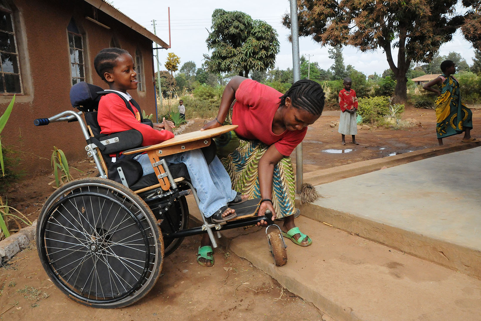 Una donna aiuta una ragazza in sedia a rotelle a salire la scala.
